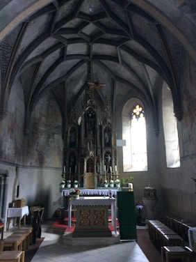 A dimly lit gothic church interior with shadowy figures and flickering candles.