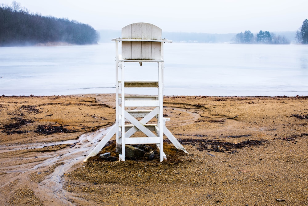 photo of white wooden lifeguard house near body of wate