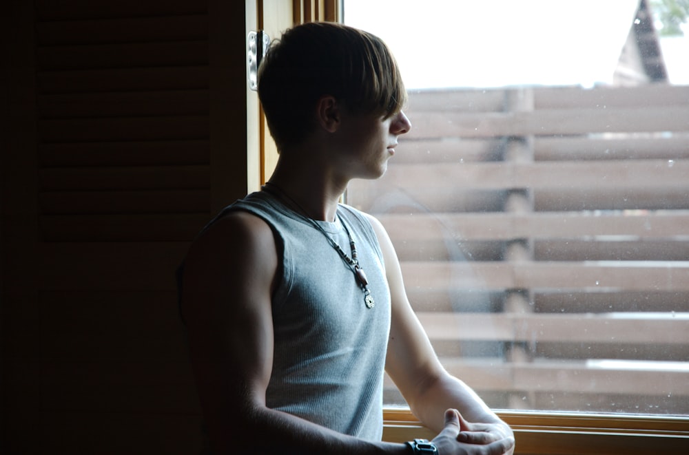 man in blue tank top looking at window