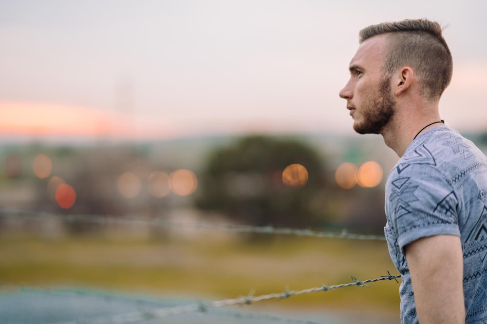 man wearing gray leaning on barbwire