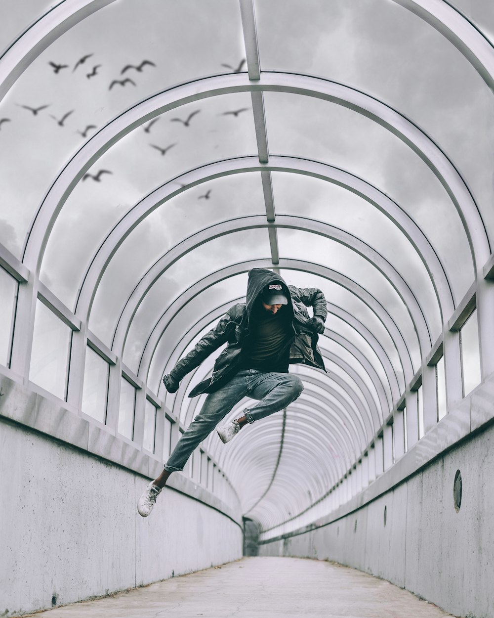 person jumping inside concrete narrow pathway during daytime