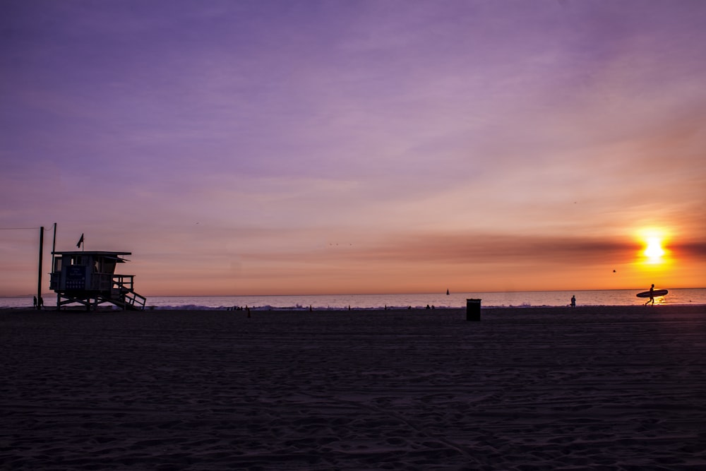 Fotografia da silhueta da casa perto do mar ao pôr do sol
