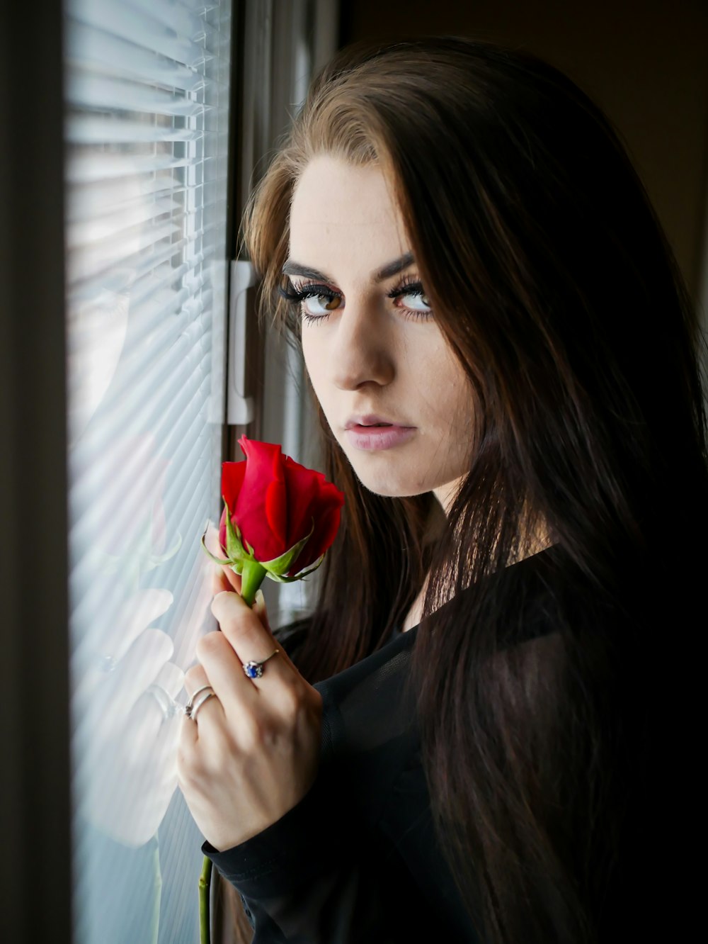 Mujer en blusa negra de manga larga sosteniendo una rosa roja