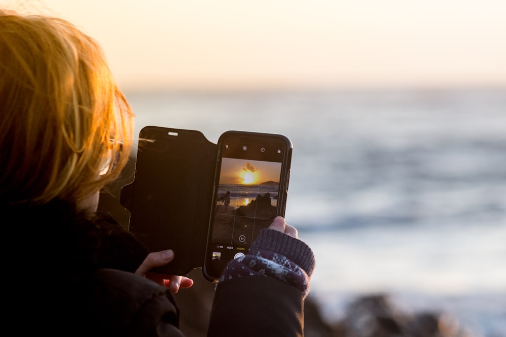 スマートフォンで夕日を捉える女性