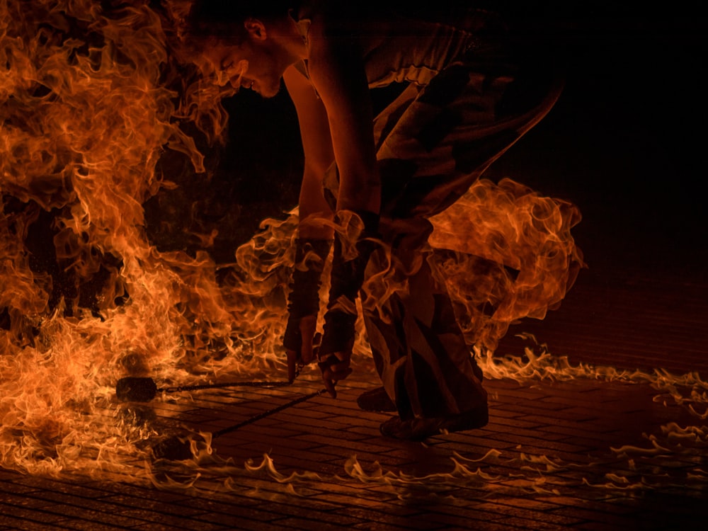 dançarino de fogo masculino segurando duas tochas cercadas por fogo