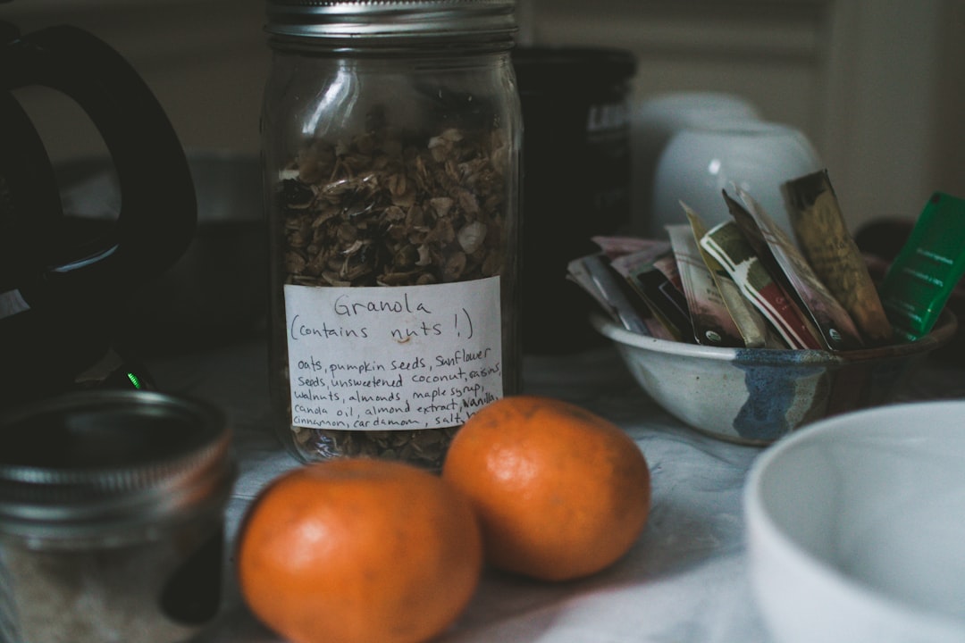 two orange fruits beside Granola labeled clear glass jar,