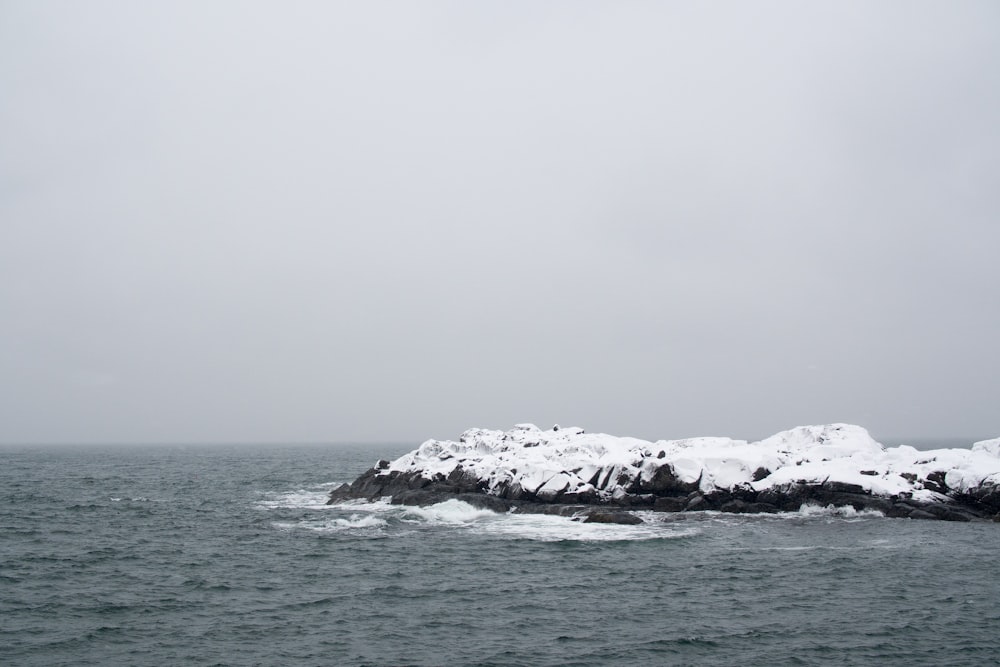 landscape photography of snow-covered rock formation surrounded by body of water