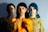 Three overlapping images of the same person with different lighting and colors. The leftmost figure is dimly lit, the middle figure is bathed in warm light with floral texture, and the rightmost figure wears a sunflower-patterned shirt.
