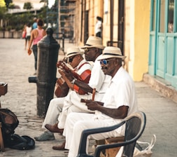 man playing acoustic guitar while sitting on bench