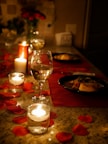 A beautifully arranged dining table set for a romantic dinner with candles and flowers.
