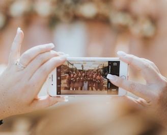 person holding iPhone capturing group of women