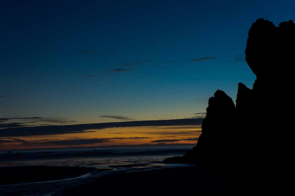 landscape photography of rock formation near body of water during nightime