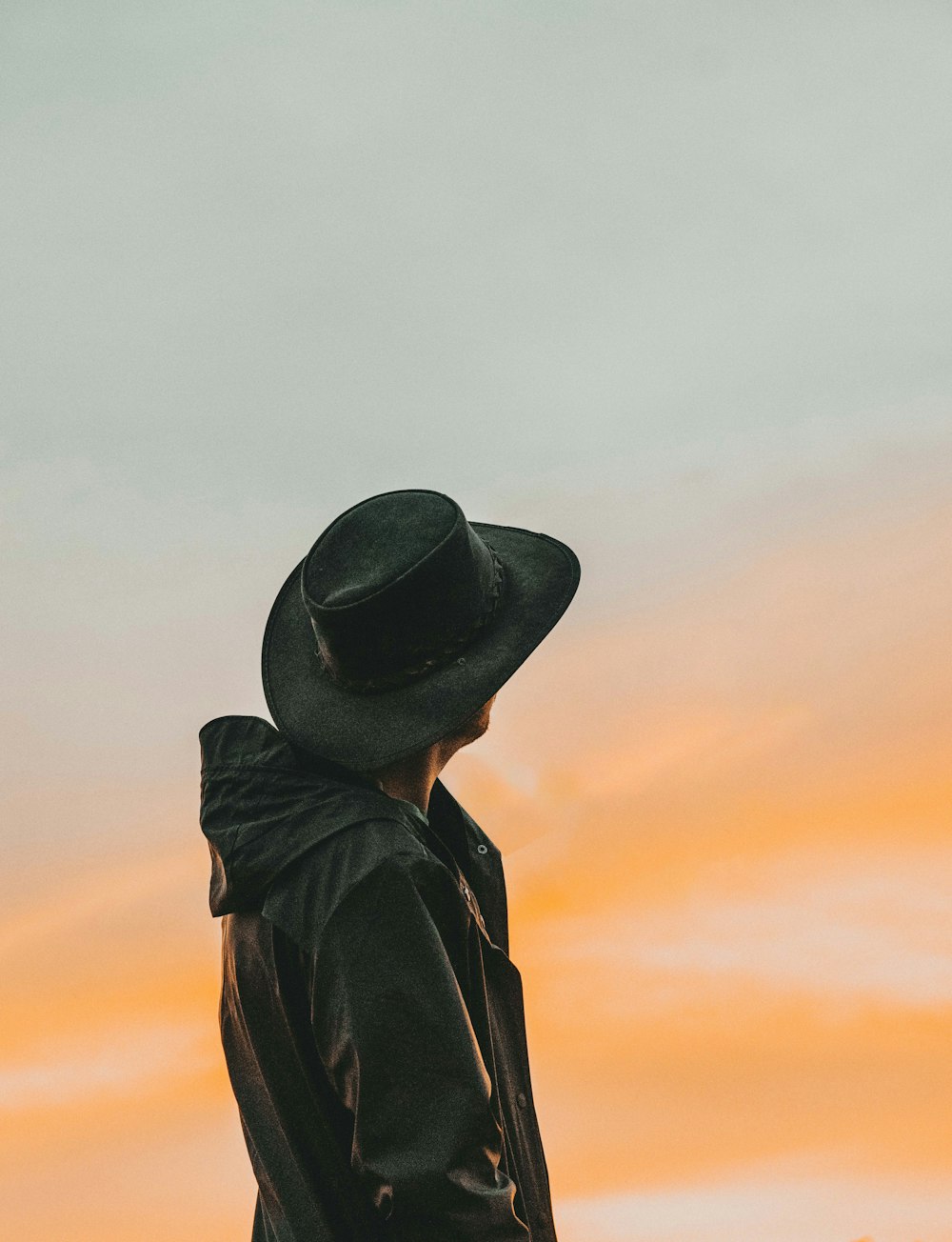 close-up photography of man wears black cowboy hat while looking up