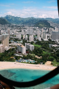aerial photo of city high rise building and seashore under cloudy sky during daytime