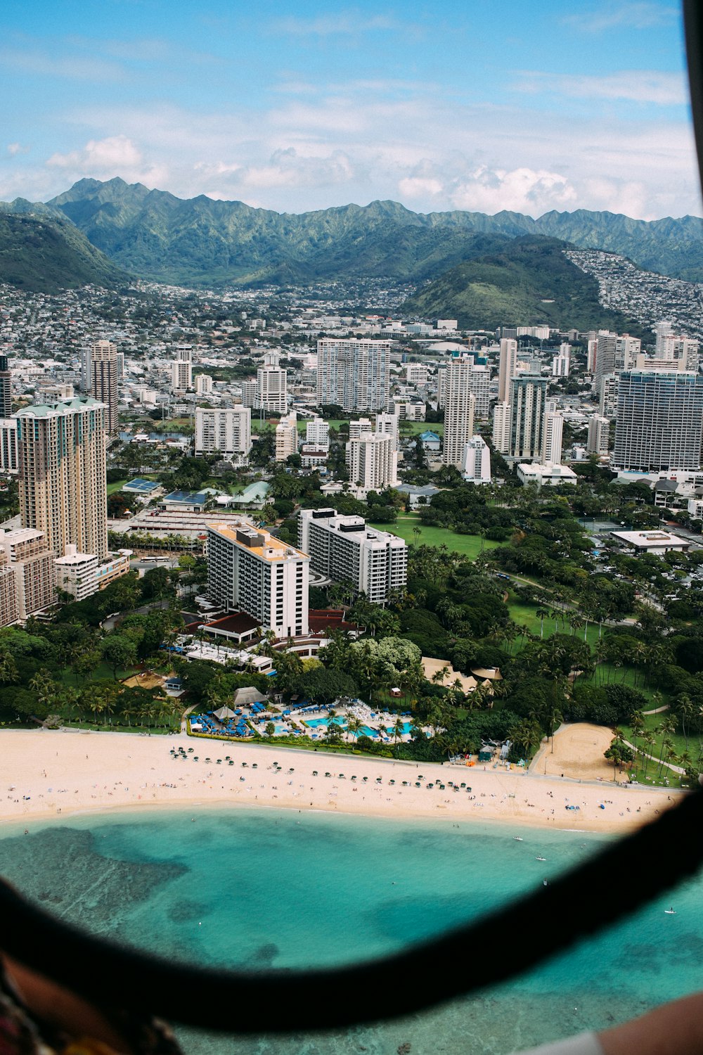 aerial photo of city high rise building and seashore under cloudy sky during daytime