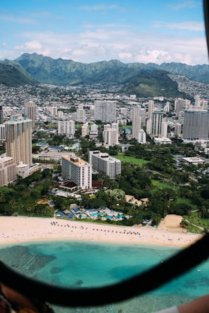 aerial photo of city high rise building and seashore under cloudy sky during daytime
