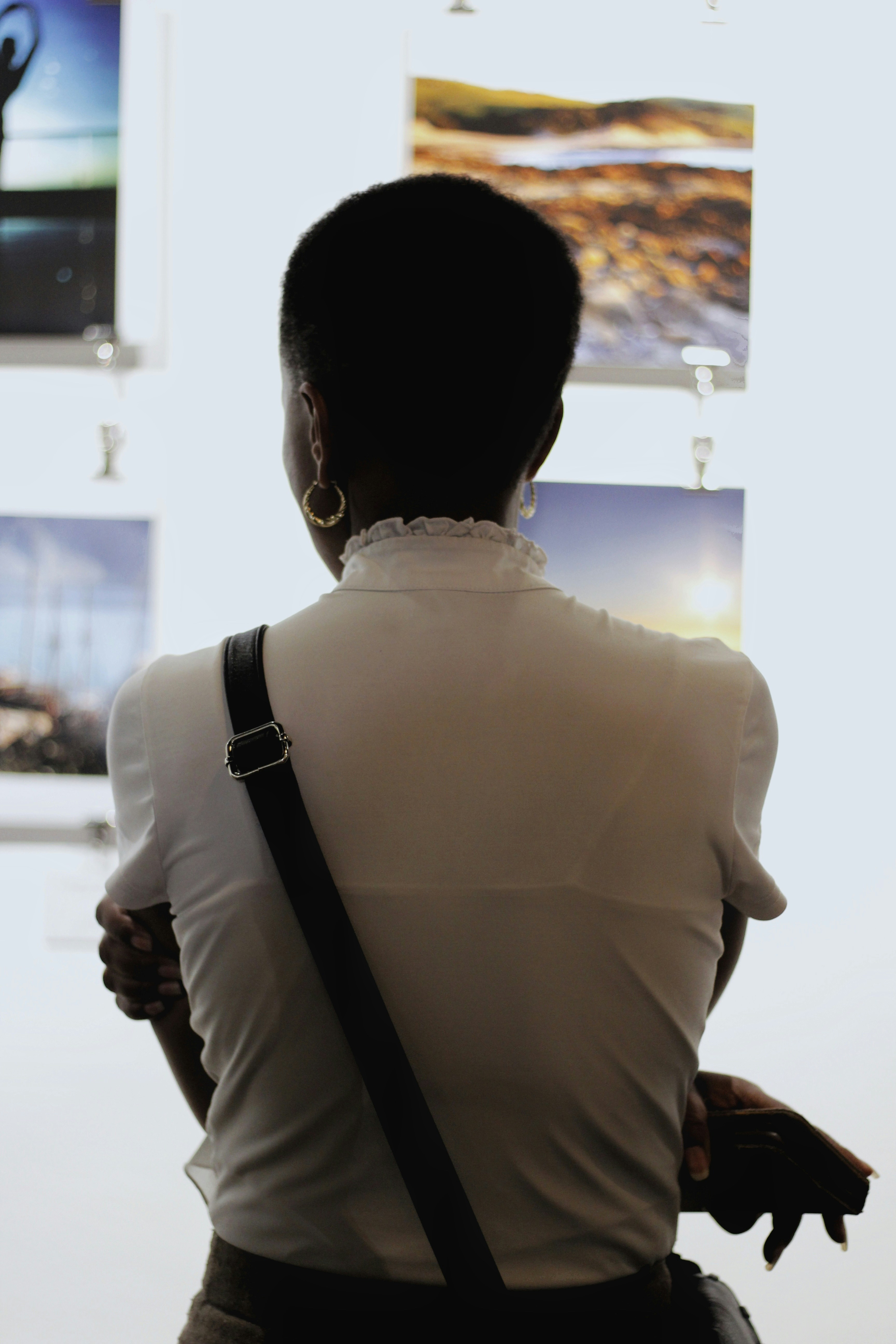 shallow focus photography of woman crossing her both arms while looking images in wall