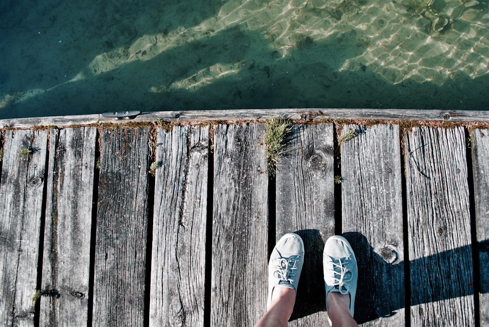 person standing on wooden dock over body of water