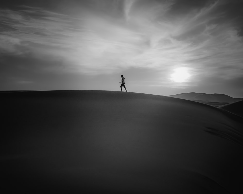 grayscale photography of man running on desert field during daytime