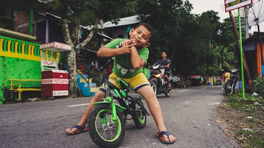boy riding black and green bike near man riding motorcycle at daytime in Sabang Indonesia