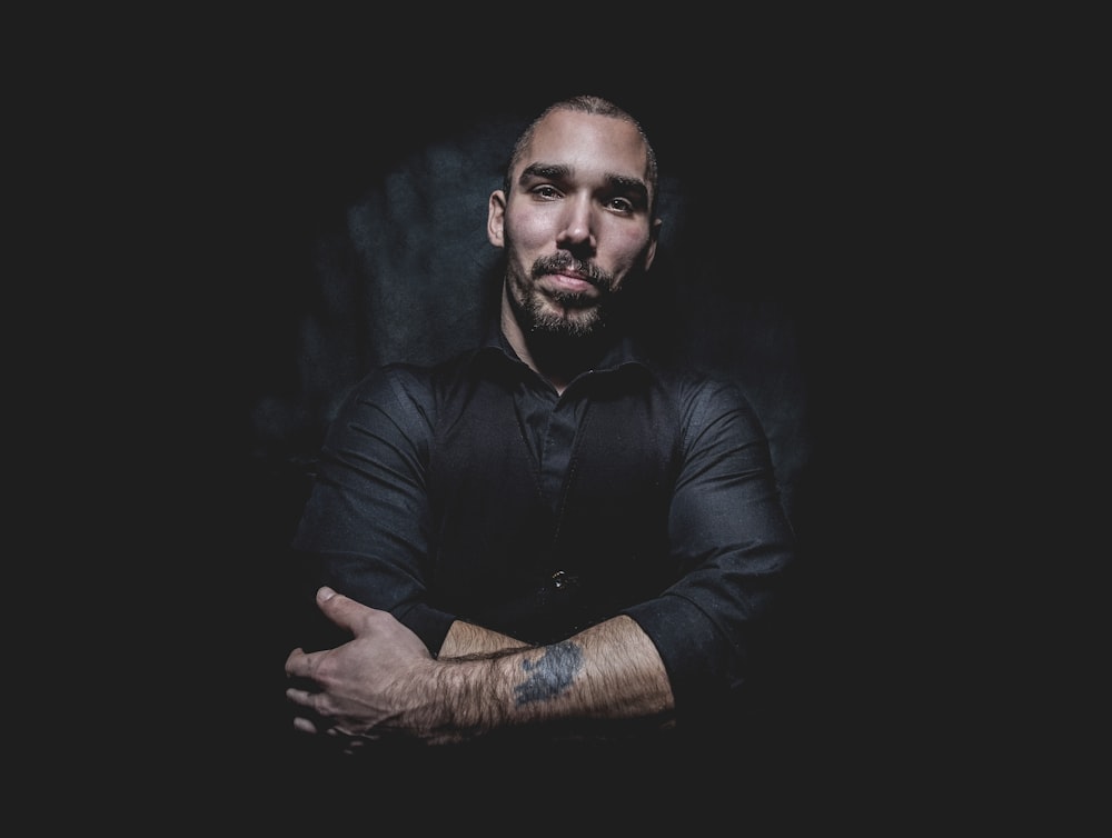 man in black dress shirt and waist coat against black background