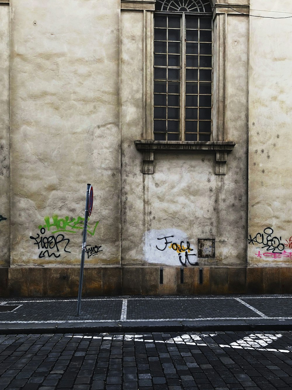 Pared vandalizada marrón y gris frente a la señalización de la calle