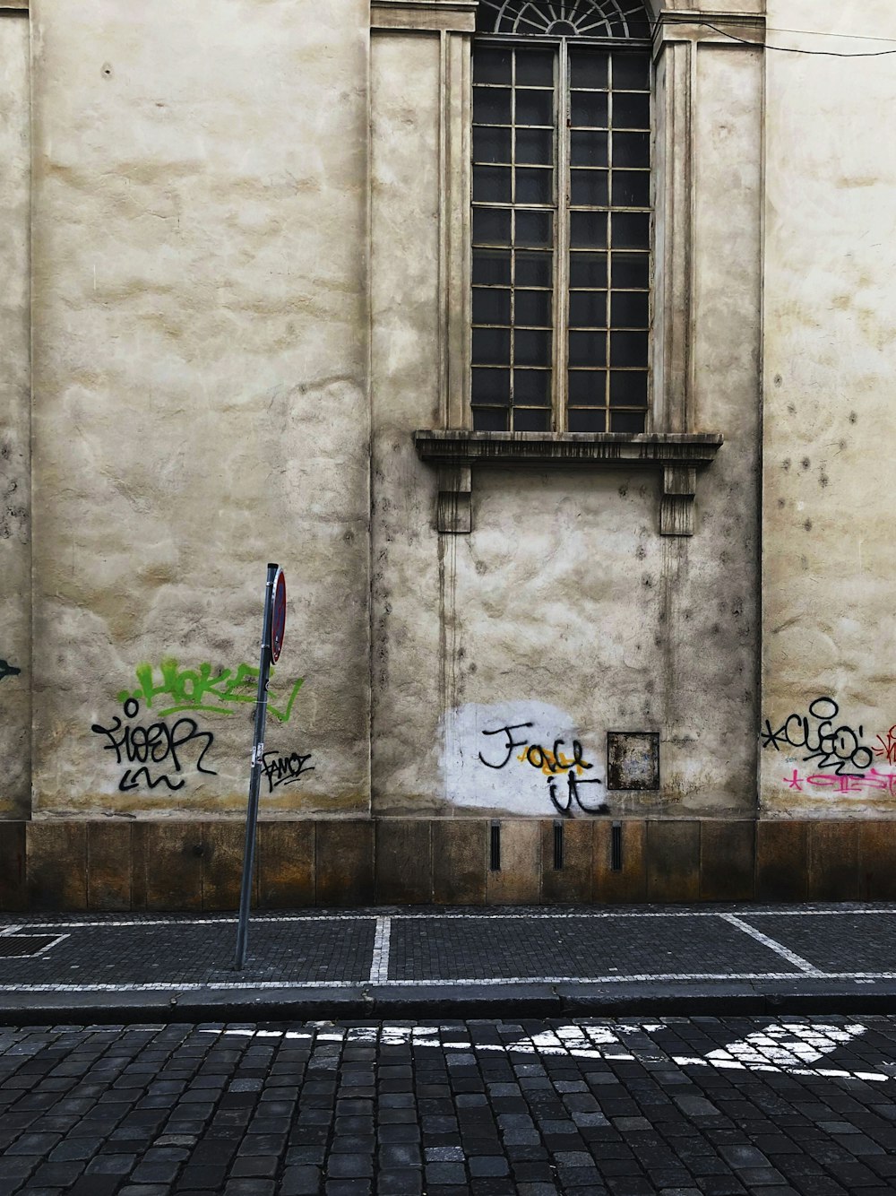 braune und graue vandalisierte Wand vor Straßenschildern