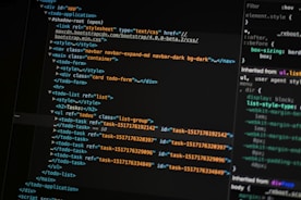 A close-up of a computer screen displays lines of HTML and CSS code. The code includes elements such as a navigation bar, container, and various task items with unique IDs. The screen also shows a styles section with properties like margin and padding.