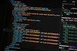 A close-up of a computer screen displays lines of HTML and CSS code. The code includes elements such as a navigation bar, container, and various task items with unique IDs. The screen also shows a styles section with properties like margin and padding.