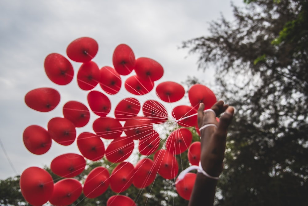 personne tenant une main de ballons rouges