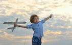 A joyful child playing with a vibrant toy airplane outdoors.
