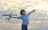 A happy child wearing a pilot jacket, holding a model airplane with a big smile