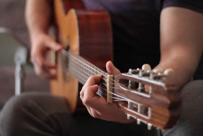 A beginner practicing simple strumming patterns on a wooden guitar.