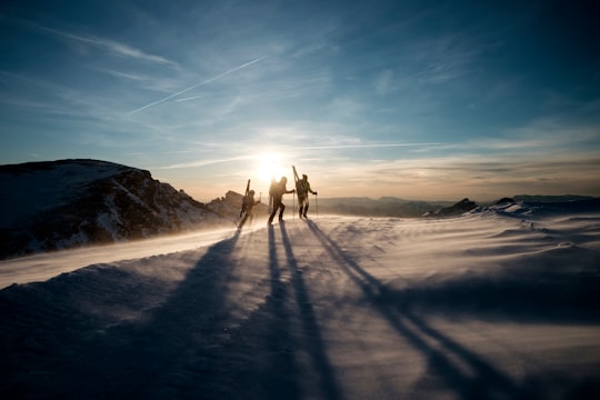three people walking on snow-capped mountain during daytime in Plateau de Bure Interferometer France
