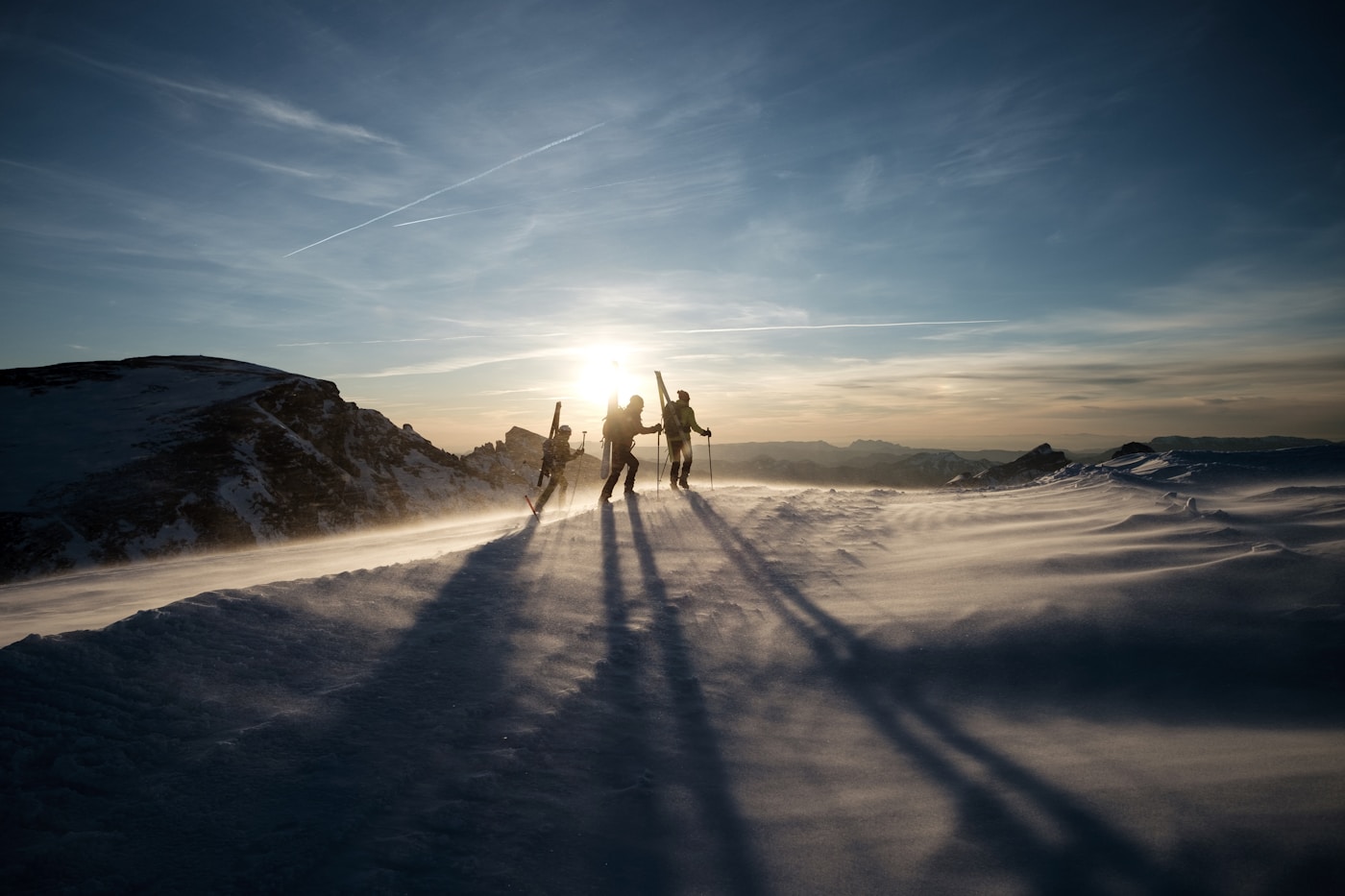 Ski tourers on a snow-capped mountain at sunset