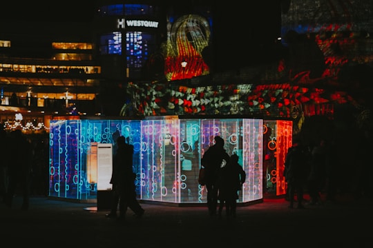 A glowing LED lightbox illuminating a vibrant retail booth during an evening event.