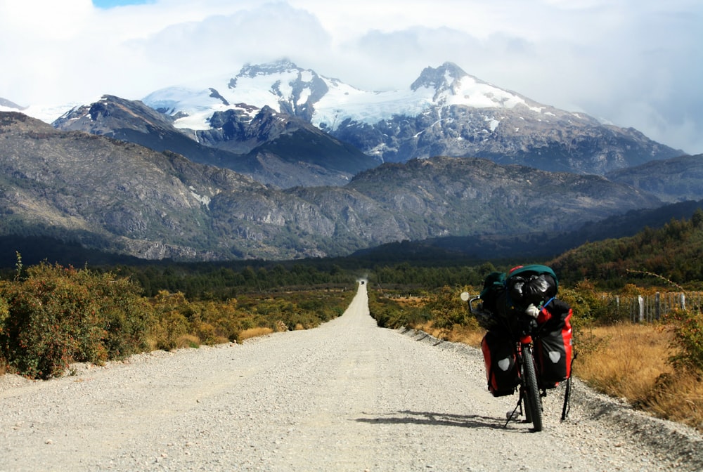 낮에 빙하 산으로 향하는 도로에 주차된 검은색 오토바이 사진