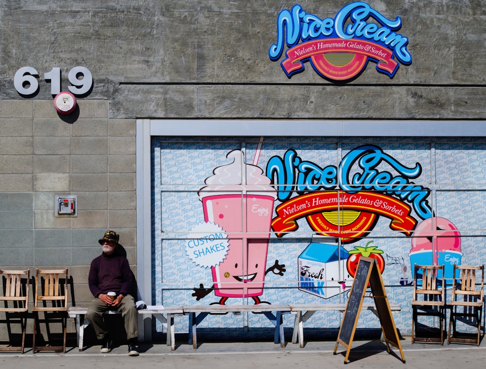 man sitting on bench while leaning on wall