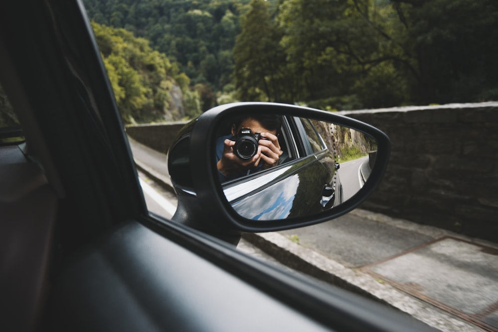 Persona que toma una foto en el espejo retrovisor negro del automóvil