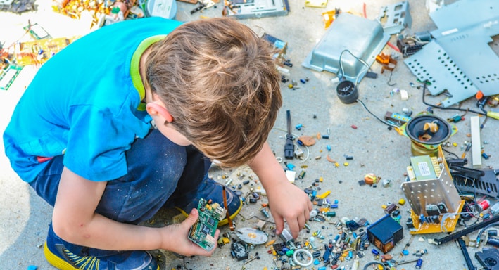 boy sitting while holding electronic device part