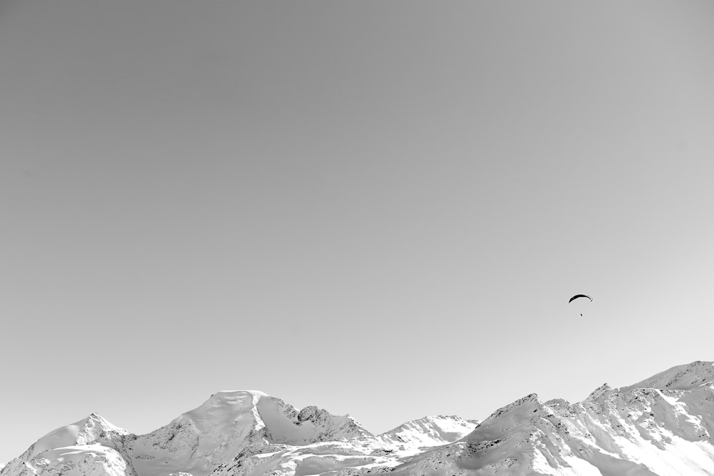 雪山の上をパラシュートで飛ぶ人