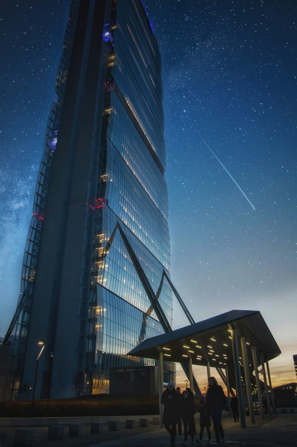 별이 빛나는 하늘 아래 커튼 월 고층 건물 근처를 걷는 사람들