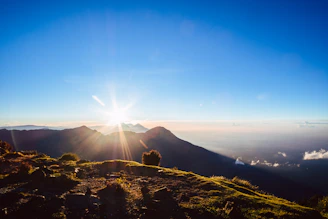 A breathtaking sunrise over Mount Rinjani, with golden light illuminating the rugged landscape.