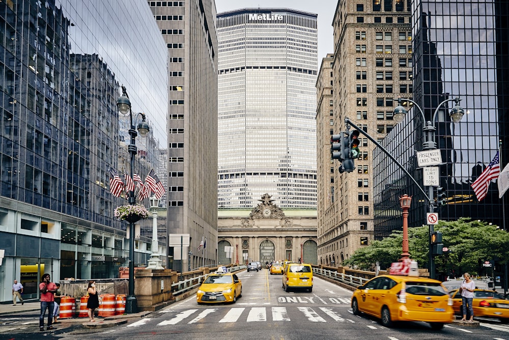 people and cars on street near high rise buildings during daytime