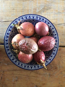 Close-up of fresh Genipa americana fruits and a bowl of natural Jagua gel on a rustic wooden table.