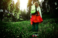 A compact, lightweight backpack worn by a person walking through a sunlit park.