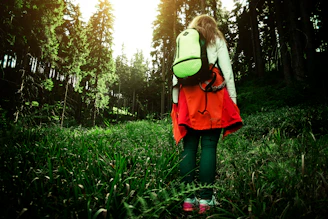 A compact, lightweight backpack worn by a person walking through a sunlit park.