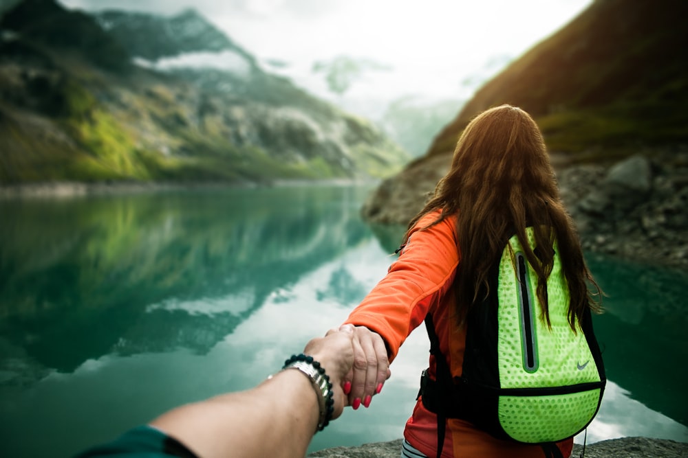 woman holding man's hand in front of water