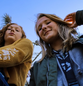 two women posing and looking down at the camera