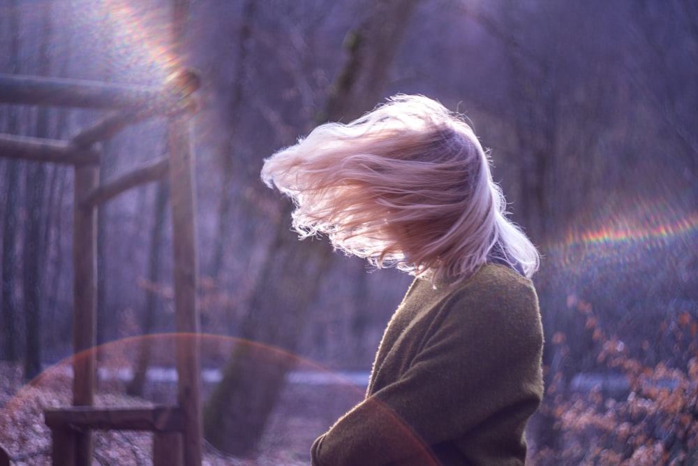 woman covering her face with hair with trees background